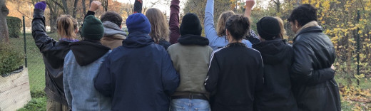 Eine Gruppe Menschen steht mit dem Rücken zur Kamera und reckt die Fäuste in die Höhe